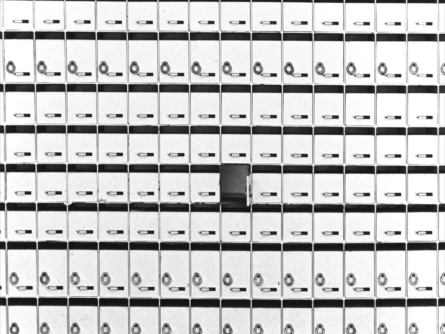 A wall of identical locked mailboxes with a single door standing open